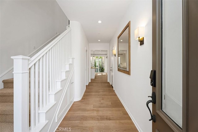 hall featuring light wood-style floors, baseboards, stairway, and recessed lighting