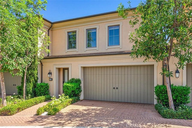 multi unit property featuring a garage, decorative driveway, and stucco siding