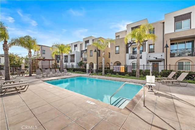 community pool with a patio area, fence, and a residential view