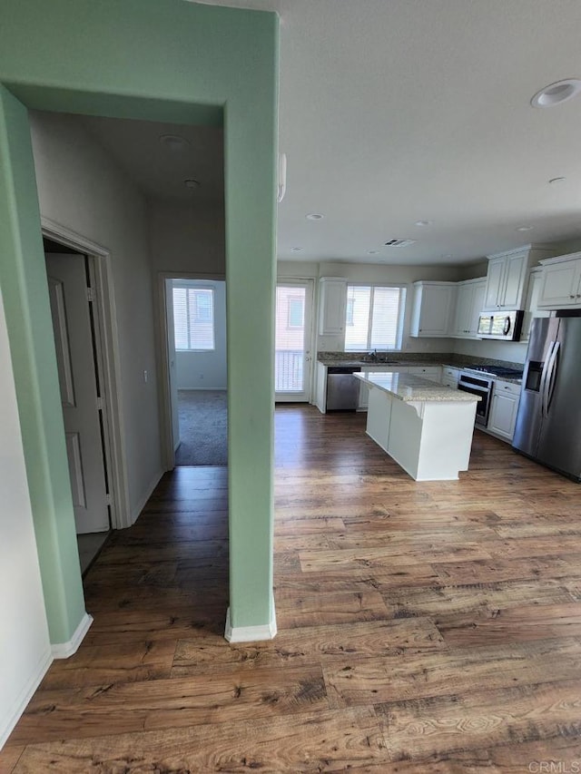 kitchen with a wealth of natural light, white cabinets, appliances with stainless steel finishes, and dark wood-type flooring