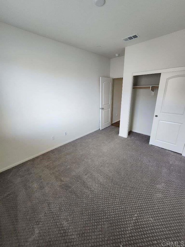 unfurnished bedroom with carpet flooring, a closet, visible vents, and baseboards