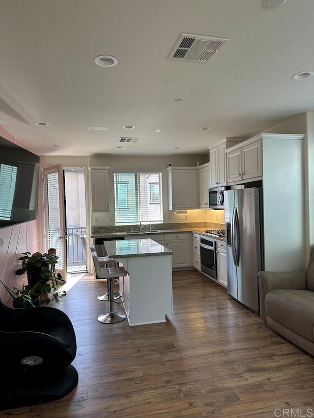 kitchen with a sink, a center island, visible vents, white cabinets, and appliances with stainless steel finishes