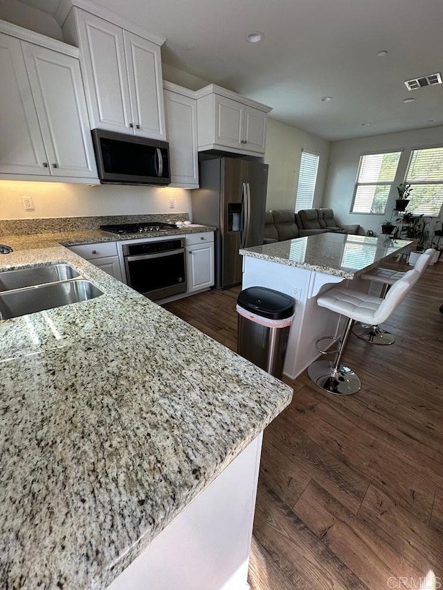 kitchen with white cabinets, visible vents, light stone countertops, and appliances with stainless steel finishes