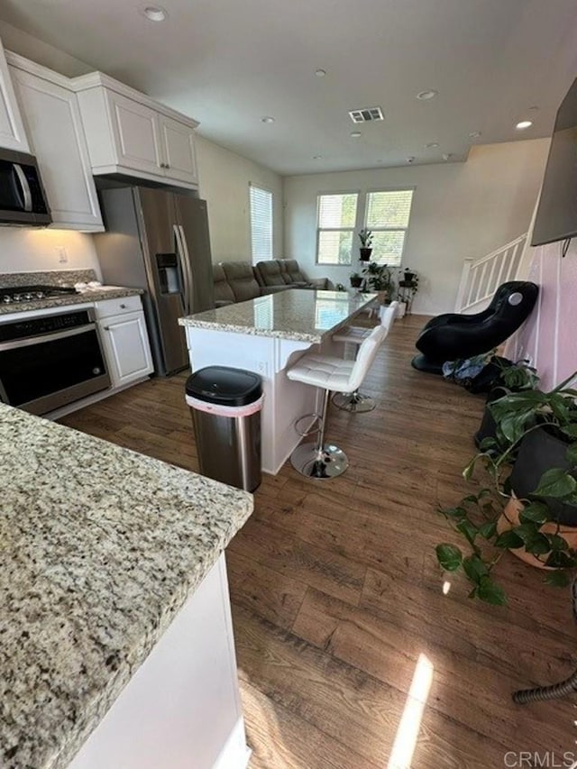 kitchen with recessed lighting, light stone countertops, stainless steel appliances, visible vents, and white cabinetry