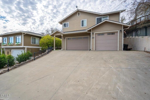 view of front of property featuring concrete driveway, an attached garage, and fence