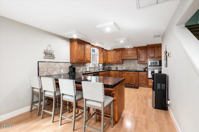 2438 Captains Walk, Bradley, CA 93426 - kitchen featuring brown cabinetry, stainless steel appliances, a peninsula, a breakfast bar, and tasteful backsplash