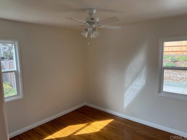 spare room with plenty of natural light, baseboards, and wood finished floors