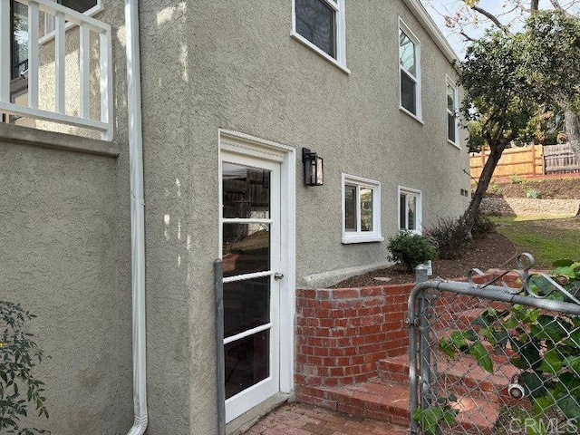 entrance to property with fence and stucco siding