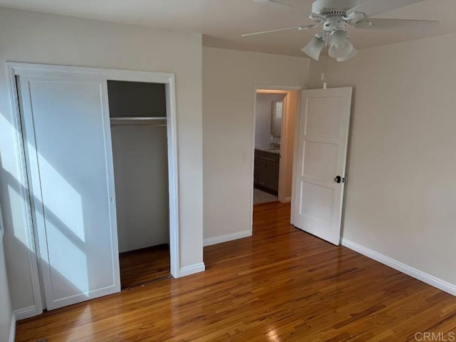 unfurnished bedroom with a closet, a ceiling fan, baseboards, and wood finished floors