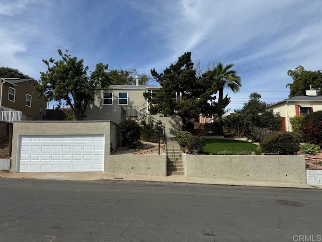 view of front of home with stairway, stucco siding, and a garage