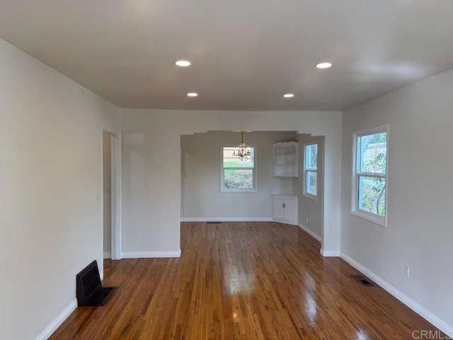 spare room featuring recessed lighting, wood finished floors, visible vents, and baseboards