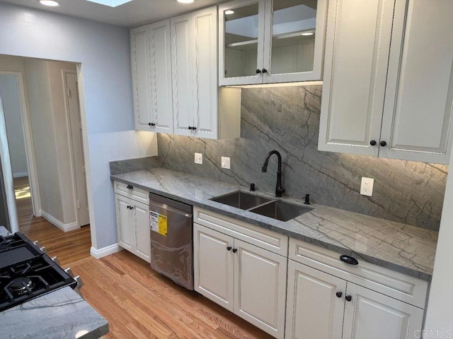 kitchen featuring stainless steel dishwasher, white cabinetry, and a sink