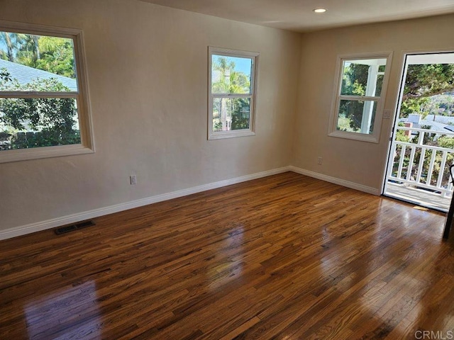 empty room with visible vents, baseboards, and dark wood-type flooring