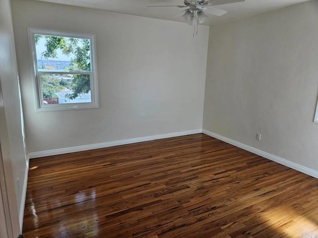 unfurnished room featuring dark wood finished floors, a ceiling fan, and baseboards