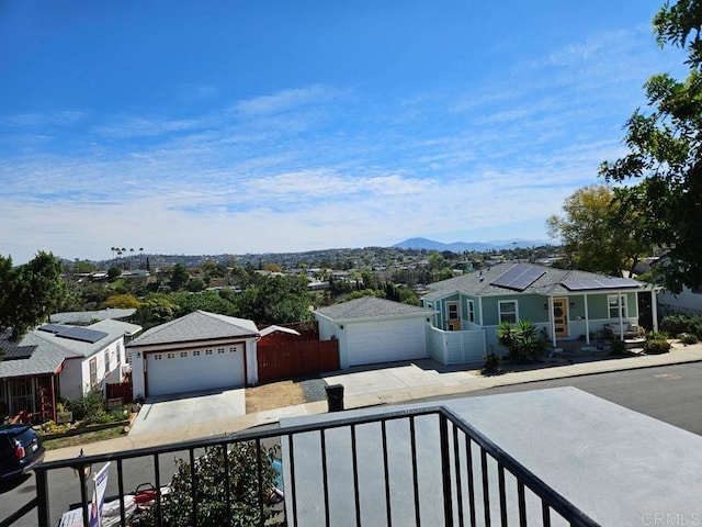 ranch-style home with fence, solar panels, an attached garage, concrete driveway, and a mountain view