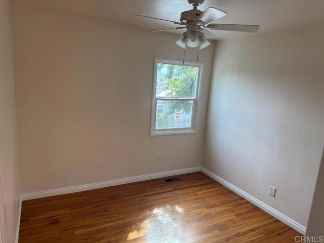 spare room with a ceiling fan, light wood-type flooring, and baseboards