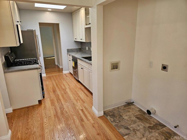 kitchen featuring tasteful backsplash, light wood-style flooring, a skylight, white cabinets, and open shelves