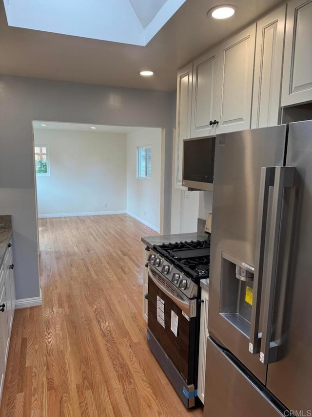 kitchen with plenty of natural light, baseboards, light wood-type flooring, and appliances with stainless steel finishes