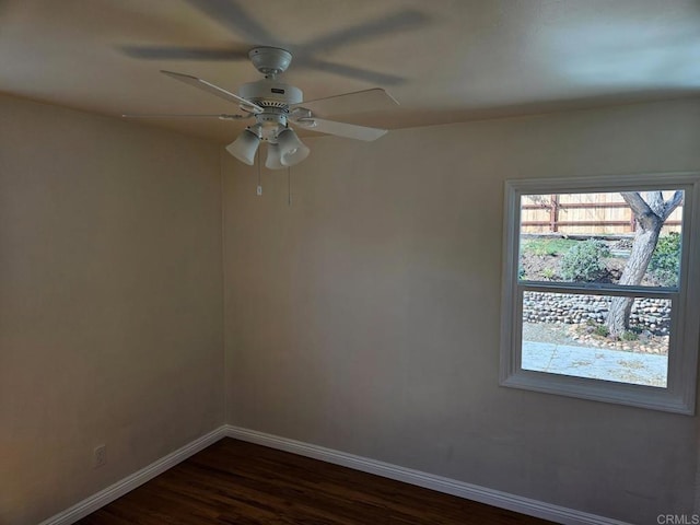 unfurnished room with a ceiling fan, dark wood-type flooring, and baseboards