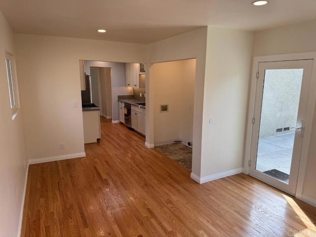 interior space featuring baseboards, dark countertops, white cabinets, and light wood finished floors