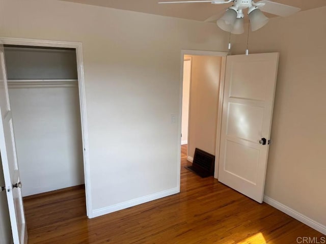 unfurnished bedroom with wood finished floors, baseboards, and a closet