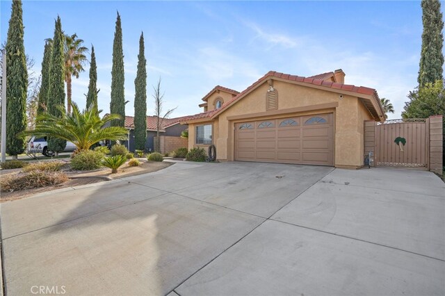 36857 42nd St E, Palmdale, CA 93552 - view of front of home featuring a garage, concrete driveway, a tiled roof, a gate, and stucco siding