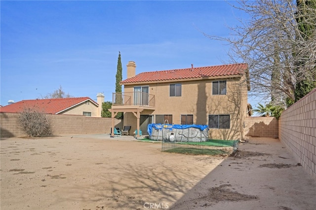 36857 42nd St E, Palmdale, CA 93552 - rear view of house featuring a balcony, a fenced backyard, a chimney, and stucco siding