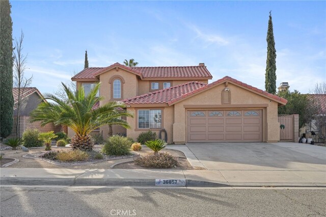 36857 42nd St E, Palmdale, CA 93552 - mediterranean / spanish-style home with concrete driveway, a tile roof, an attached garage, and stucco siding