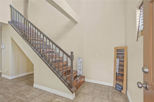 stairs featuring a high ceiling, baseboards, and tile patterned floors