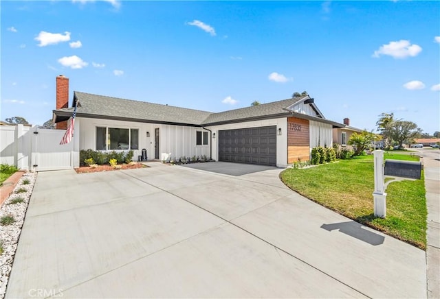 ranch-style home featuring a garage, concrete driveway, a gate, a front lawn, and board and batten siding