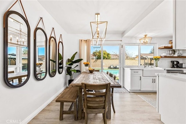 dining room featuring light wood-style flooring, a chandelier, and baseboards