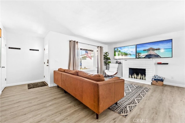 living area with light wood-style floors, a fireplace, and baseboards