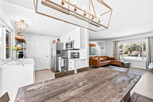 kitchen with light wood finished floors, appliances with stainless steel finishes, white cabinets, and light countertops