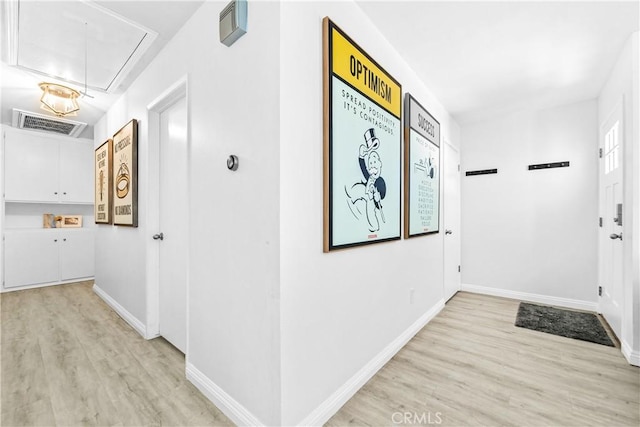 corridor with attic access, baseboards, visible vents, and light wood finished floors