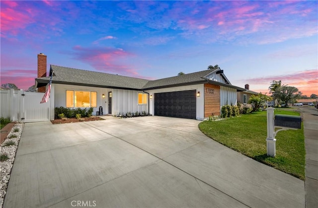 ranch-style house featuring a garage, a yard, concrete driveway, a gate, and a chimney