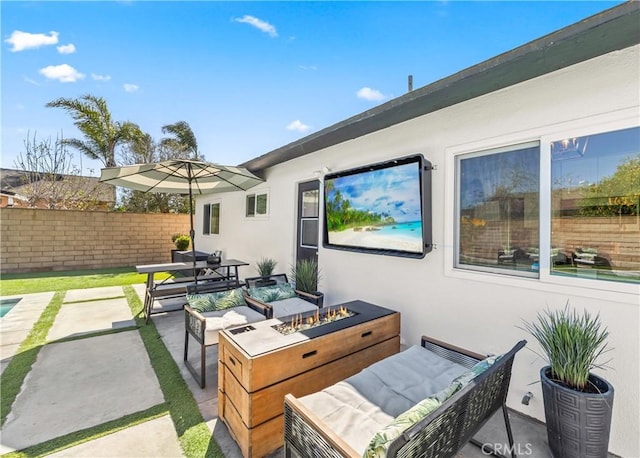 view of patio with an outdoor living space with a fire pit and fence