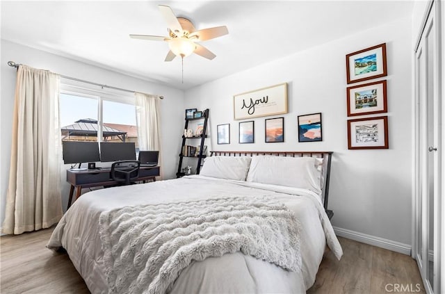 bedroom with a ceiling fan, baseboards, and wood finished floors