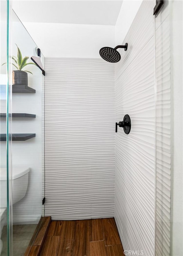 bathroom featuring tiled shower, toilet, and wood finished floors