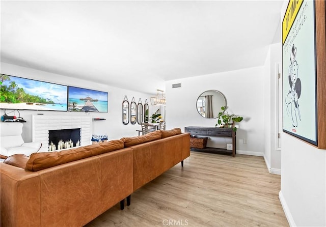 living room featuring baseboards, a fireplace, visible vents, and light wood-style floors