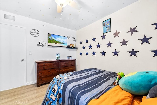 bedroom with ceiling fan, wood finished floors, and visible vents