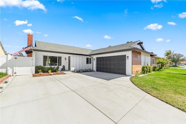 ranch-style home with concrete driveway, an attached garage, a gate, a front lawn, and board and batten siding