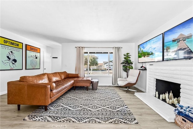 living area with a brick fireplace, baseboards, and wood finished floors