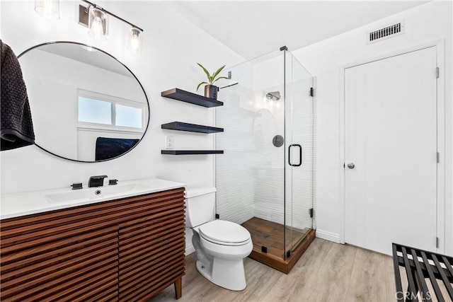 full bath featuring toilet, a shower stall, visible vents, and wood finished floors