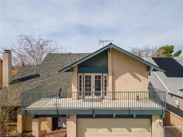 rear view of property with french doors, an attached garage, and stucco siding