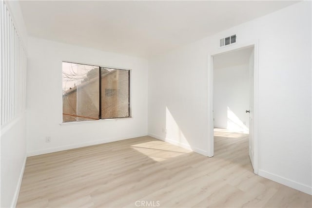 spare room with baseboards, visible vents, and light wood-style floors