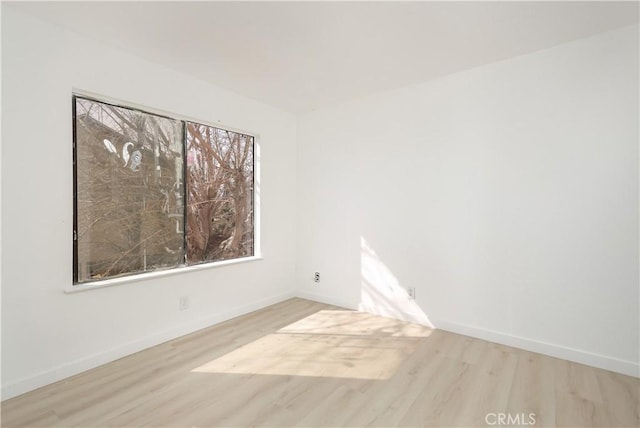 spare room featuring plenty of natural light, baseboards, and wood finished floors