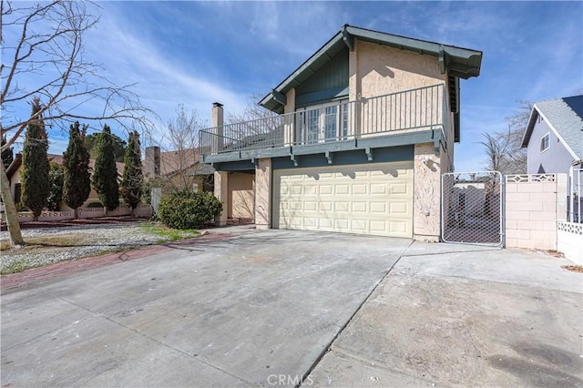 view of front of home featuring stucco siding, concrete driveway, fence, a balcony, and a garage