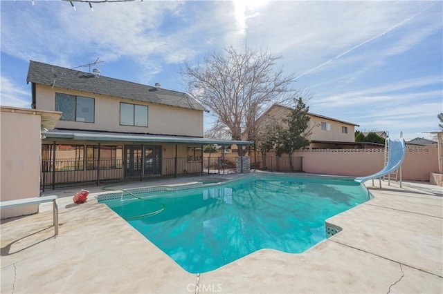 view of swimming pool featuring a patio, a water slide, fence, and a fenced in pool