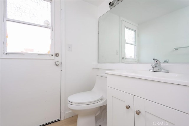 half bathroom featuring vanity, toilet, and wood finished floors