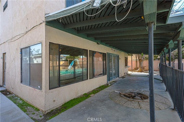 view of home's exterior featuring a fire pit, a patio area, fence, and stucco siding